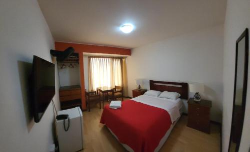 皮斯科Hostal El Candelabro的一间卧室配有一张带红色毯子的床