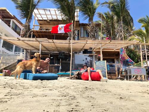 曼克拉Wiracocha Hostal Máncora - Surf Camp的一只狗和人们一起站在海滩上