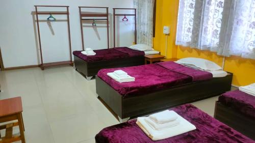 因帕尔Iranyai Homestay的带紫色床单的客房内的三张床