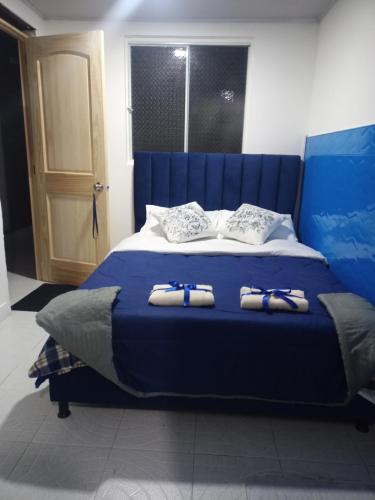 波哥大House Beautiful Horizon P1的一张蓝色的床,上面有两双拖鞋