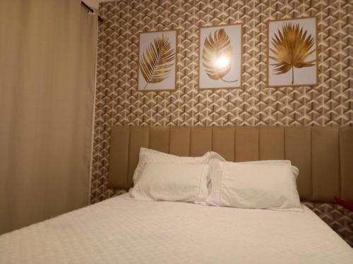瓜鲁雅Suíte Studio 3 Enseada Tortuga Mobiliada的卧室配有一张四幅画的墙壁床。