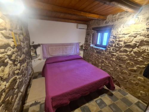 UsellusCasa di Pietra的小房间,在石墙里设有一张紫色的床
