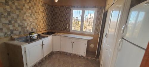 苏塞Dar souade chatt mariem的厨房配有白色橱柜、水槽和窗户。
