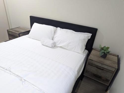 格拉德斯通Christa's 4Bedroom Entire Private House Gladstone City的一张带黑色床头板和白色枕头的白色床