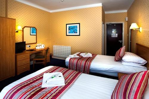 伯恩茅斯Devon Towers Hotel的酒店客房配有两张床和一张书桌