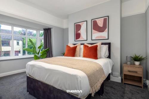 莱姆河下游的纽卡尔斯NEW Poplar House - Stunning 4 Bedroom House in Stoke-on-Trent的一间卧室配有一张带橙色枕头的大床