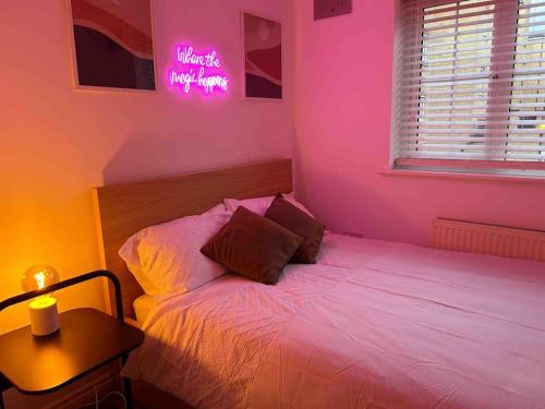 罗姆福特East London Apartment near Station & Free Parking, Arcade Machine的粉红色的卧室,配有床和 ⁇ 虹灯标志