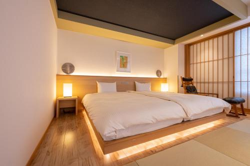 山之内町苏米诺卢酒店的一间卧室配有一张带两盏灯的大型白色床。