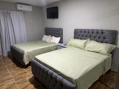 蒙特克里斯蒂省圣费尔南多Aparta Hotel Esa Buya的一间卧室设有两张床,墙上配有电视。
