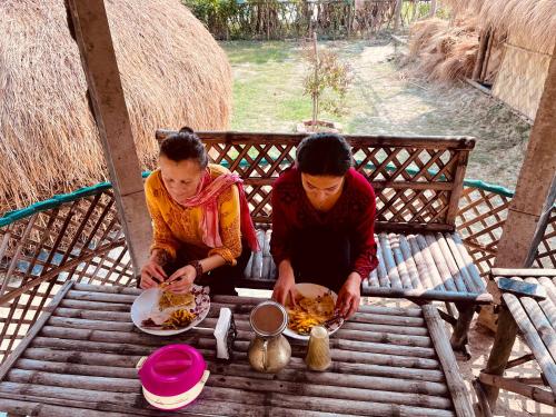 KākdwīpSatrangi Homestay Sundarban的两个人坐在桌子上吃食物