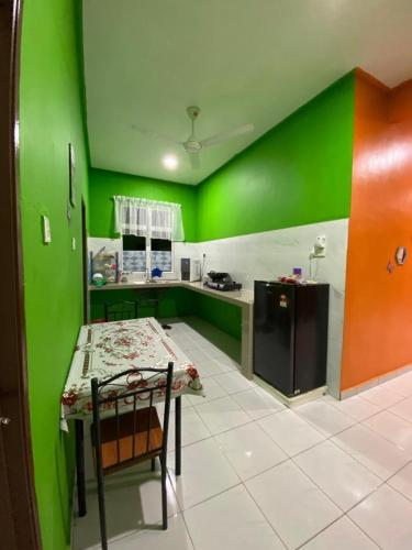 巴佐Pelangi Homestay 2的厨房设有绿色的墙壁和桌椅