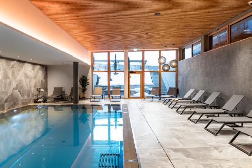 奥贝劳Landhotel Tirolerhof - Mai bis Mitte Juni kein Saunabetrieb的一个带椅子的室内游泳池和游泳池