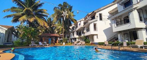 阿伯来Susegad Suites Goa Apartments & Villas Riviera Hermitage Arpora的一座有人居住的建筑前的游泳池