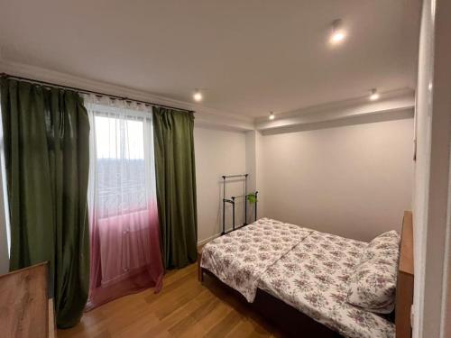 SamgoriCosy Apartment in Varketili的一间卧室设有床铺和一个带绿色窗帘的窗户。