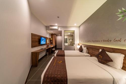胡志明市Thanh Long Hotel - Bach Dang的一间酒店客房,设有两张床和电视