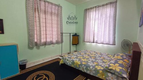 马六甲Casatiga Pool Homestay in Melaka Musliim Only的一间卧室设有一张床和两个窗户。