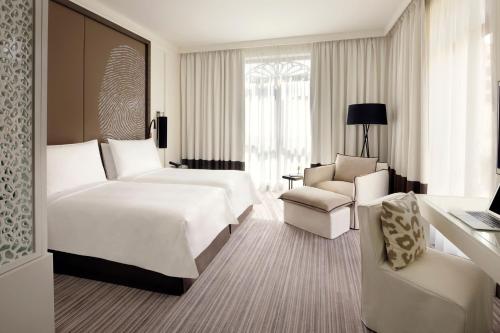 迪拜Hotel Boulevard, Autograph Collection的酒店客房,配有两张床和椅子