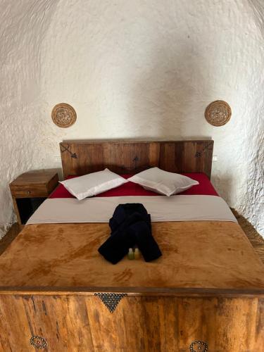 MatmataLars homestead的一张带两个枕头的木床和一顶帽子