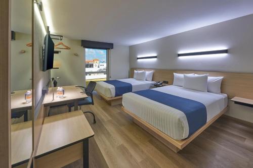 坎昆City Express by Marriott Cancun Aeropuerto的酒店客房设有两张床和电视。