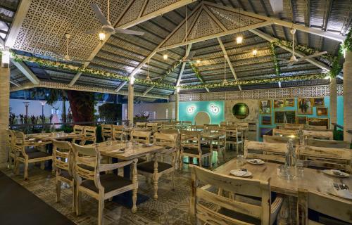 戈尔哈布尔Ramee Panchshil的餐厅设有木桌、椅子和天花板