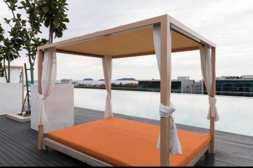 哥打京那巴鲁Hstay Sutera Avenue 2Bedroom by Aida的游泳池畔的甲板上的橙色床