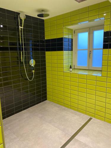 里姆斯廷格Beim Has’n的浴室设有黄色和黑色瓷砖以及淋浴。