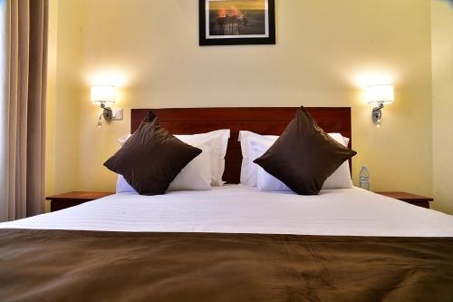 恩德培ENTEBBE STAY Apart-Hotel的卧室配有一张带白色床单和枕头的大床。