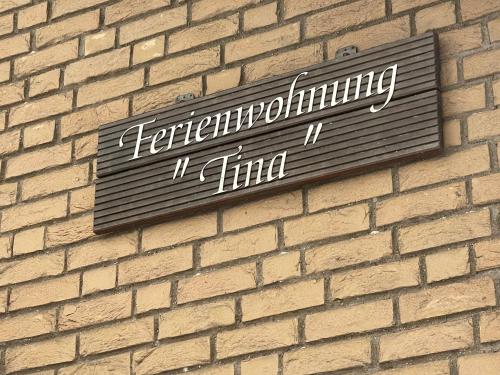 NettersheimFerienwohnung Tina的砖墙边的标志