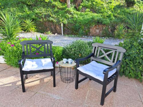 波尔蒂芒Casa Rochinha的两张黑椅子坐在桌子旁,边有一张桌子边