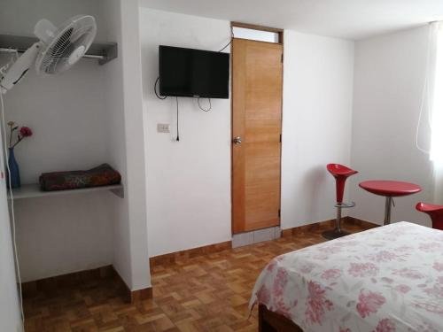 特鲁希略Hotel Huanchaco的一间卧室配有一张床、一台电视和一张凳子
