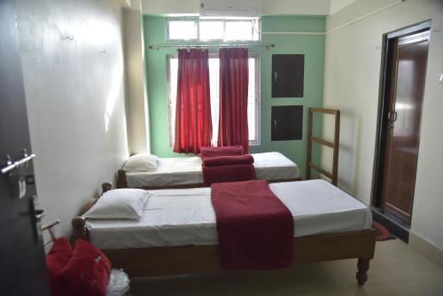 古瓦哈提Bibhas Lodge & Restaurant的配有红色窗帘的客房内的两张床