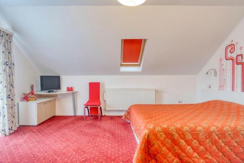 莫伊西德约斯Casa Preto E Branco的一间卧室配有一张床、一张桌子和一把红色椅子