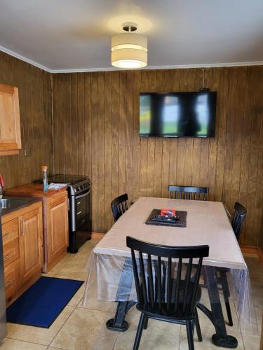 锡斯内斯港Cabañas kawi的厨房配有桌椅和墙上的电视