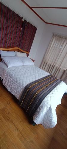 HuillanopampaTaquile Lodge Inn的一间卧室配有一张带木制床头板的床