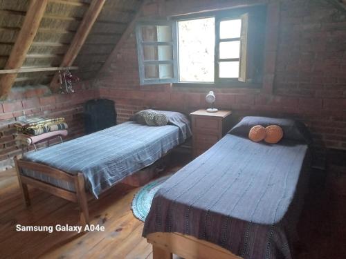 巴拉德瓦利扎斯Confortable y acogedora cabaña a 150 mts de la playa的一间卧室设有两张床和窗户。