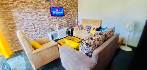 基苏木Beautiful and Affordable 1brm in Milimani的客厅设有两张沙发,砖墙上配有电视