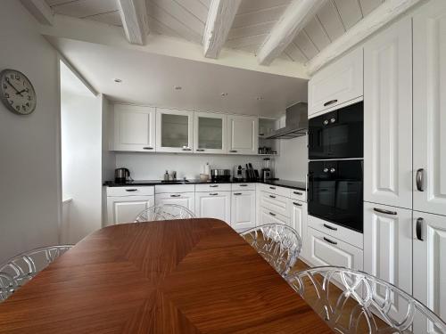 格兰瓦克斯Domaine du Deven Grandvaux的厨房配有白色橱柜和一张带椅子的木桌