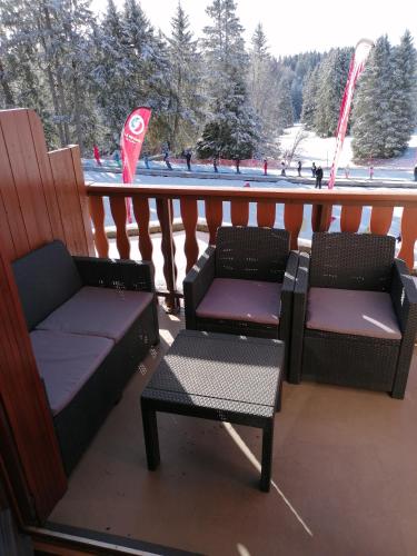 TrévigninAppartement 5 personnes en station Savoie Grand Revard的阳台配有两把椅子和一张桌子,阳台设有雪盖斜坡