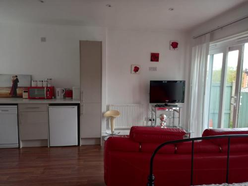 科尔切斯特Colchester Town, modern, detached, guest house的一间带红色沙发的客厅和一间厨房