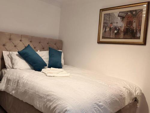 达格纳姆One small bed apartment by monishortlets的一张带蓝色枕头的床和一张墙上的照片