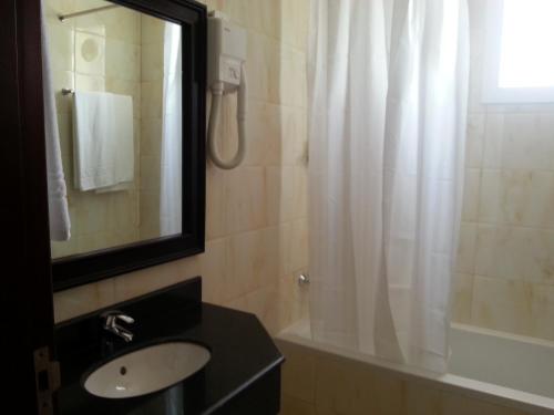 塞拉莱马斯喀特国际广场酒店的浴室配有盥洗盆和带镜子的淋浴
