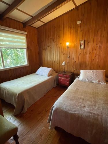 拉恩塞纳达Cabañas Vista al Lago的配有木墙和窗户的客房内的两张床