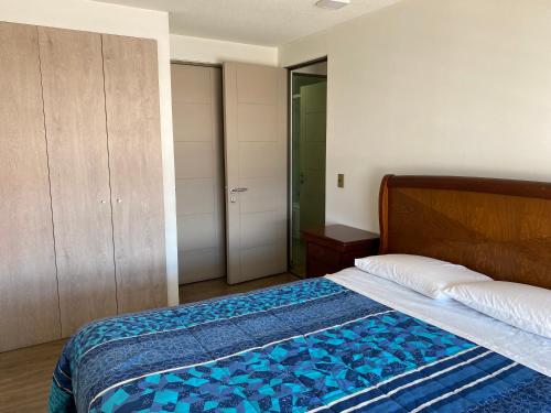 MaipoDepartamento centro Buin的一间卧室配有一张带蓝色棉被的床