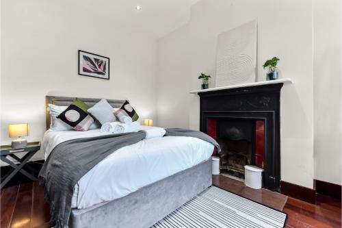 HanwellLovely 2-bedroom rental unit in Greater London的一间卧室配有一张床和一个壁炉