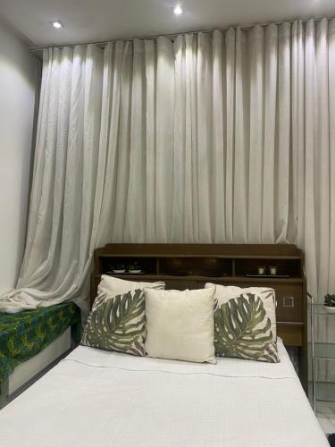 阿拉瓜伊纳Flat suítes mobiliados central的卧室内的一张带白色床单和枕头的床