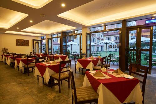 加德满都尚佰林精品酒店的餐厅设有红色和白色的桌椅和窗户。