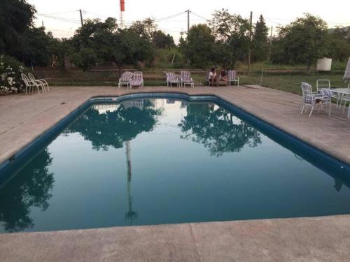 PeñaflorCasa de Campo en Malloco的一个带椅子和桌子的游泳池以及一个人坐的游泳池