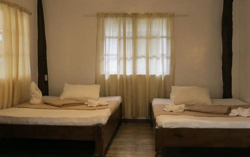 BulalakaoSouthdrive Beach Resort的带窗户的客房内设有两张单人床。