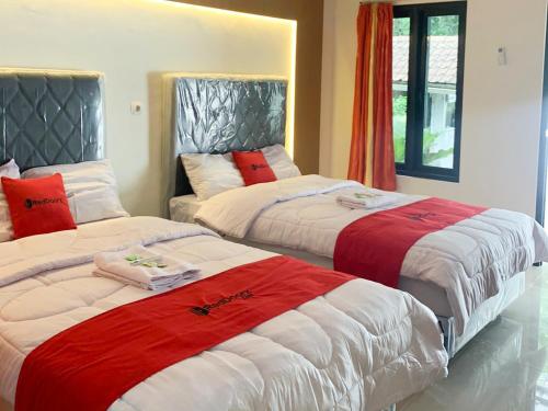 日惹RedDoorz near Museum Gunung Merapi的一间卧室配有两张红色和白色床单