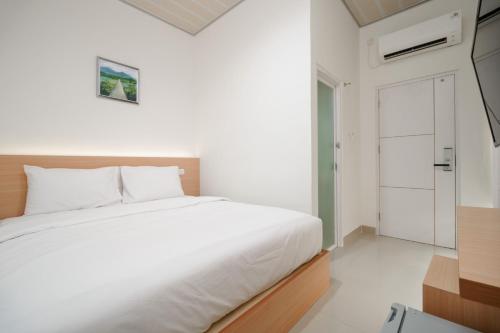 日惹Urbanview keTemon Hotel & Resto YIA by RedDoorz的一间白色的卧室,配有床和门